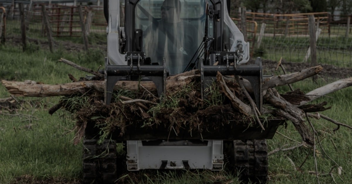 Bobcat track loader with grapple attachment clearing hurricane debris